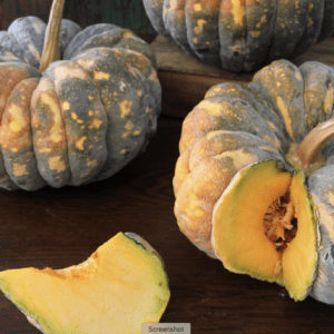 Fresh green pumpkins with one sliced showing the orange interior and seeds.